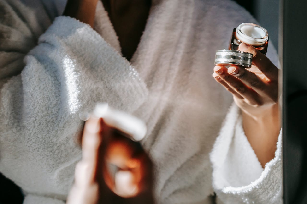 Mastering the First Impression: Your intriguing post title goes here Woman in bathrobe applying skincare cream for a calm morning routine.
